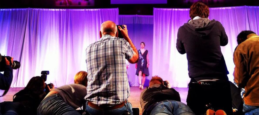 Image shows photographers taking photos of people on stage. 